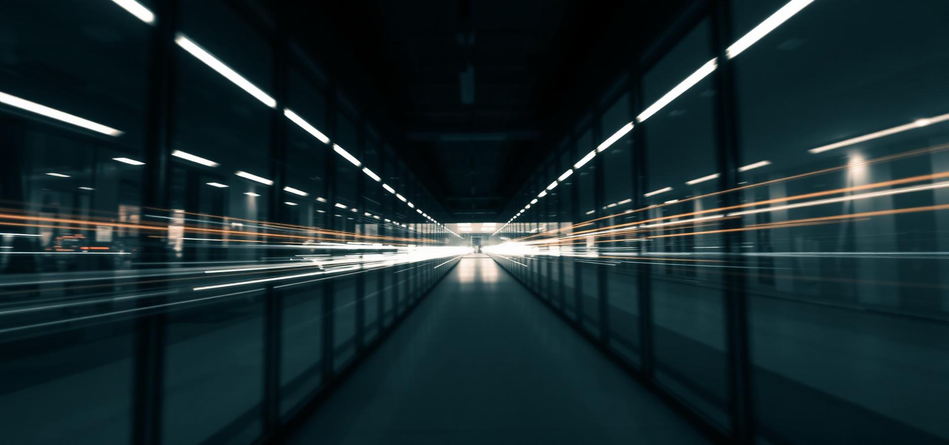 Long-exposure light trails through a glass corridor representing data moving between systems